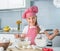 Little girl adding flour to a dough