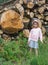 Little girl against stacked sawn wooden logs