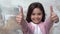 Little girl alone isolated on painted wall smiling showing thumbs up