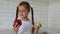 Little girl with apples in the kitchen. Child bites eating an apple