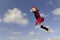 Little girl as a flying lady bug, blue sky with clouds