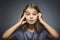 Little girl with astonished expression while standing against grey background