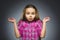 Little girl with astonished expression while standing against grey background