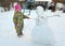 The little girl with astonishment looks at a snowman