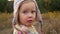 Little girl in the autumn forest. The child is somewhat agitated and worried and informs about this by turning to the