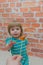 Little girl, baby with candy on stick, on brick wall background