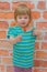 Little girl, baby with candy on stick, on brick wall background