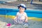 Little girl baby in a cap plays with toys in a sandbox with sand on the playground