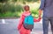 Little girl with backpack holding father's hand