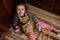 Little girl baker confectioner, chef pastry in chef apron and mittens shows thumbs up, sitting barefoot on kitchen floor