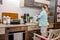 Little girl baking waffles in the kitchen following a recipe on the smartphone while standing on a chair