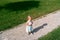 Little girl with a ball in her hand stands on the gravel path in the lawn