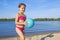 Little girl with a ball in her hands on the river, on a sunny day