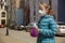 A little girl with a ball, wearing a medical mask, empty town on the background.