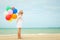 Little girl with balloons standing on the beach