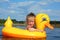 Little girl bathes in river in inflatable duck