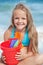 Little girl on the beach with small bucket and shovels for sand