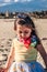 Little girl at beach, summer dressed child girl on a trunk looking down