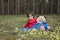 Little girl with a bear in the woods sitting on a flower meadow.