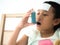Little girl on bed using blue asthma inhaler for relief asthma a