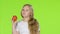 Little girl bites an apple and shows a thumbs up. Green screen