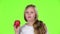 Little girl bites an apple and shows a thumbs up. Green screen. Slow motion