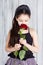 Little girl in the black dress sniffs a red rose