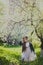 Little girl in black jacket and white dress dancing in the spring cherry garden