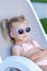 A little girl with blond hair sunbathes in sunglasses. The child is on vacation, lying on a sun lounger.