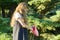 Little girl blonde with long curly hair with a pink rubber handbag in the park. The girl opened and looks in handbag