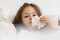 Little girl blow stuffy nose with white handkerchief. Portrait closeup of unhealthy child. Bed rest, snot, cold symptoms