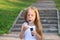 Little girl blows bubbles near stairs in green sunny park