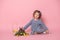 Little girl in blu dress with rabbit, tulips, basket with colorful eggs on pink background