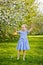 A little girl in a blue dress was walking in a blooming apple orchard. Nice spring story. Happy baby on a beautiful spring sunny