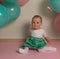 Little girl in blue and white dress next to balloons, smiling, holiday, year, birthday child. sits on the floor