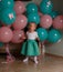 Little girl in blue and white dress next to balloons, smiling, holiday, year, birthday child. sits on the floor