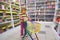 Little girl in bookshop, with cart for purchases