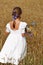 Little girl with a bouquet of wildflowers in her hands in a wheat field.