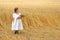 Little girl with a bouquet of wildflowers in her hands in a wheat field.