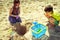 Little girl and boy with shovel have fun on beach.