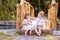 A little girl and a boy sit on a bridge over a river.