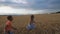 Little girl and boy standing in wheat field and releasing from hands balloon into the sky. Cute small kids having fun