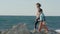 Little girl and boy walks along beach near sea, homeless children, against background ocean at sunset. kid goes together with his