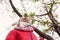 Little girl in a bright scarf sniffs a flowering tree.