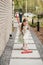 A little girl with a brush cleans a path on the street in the courtyard