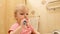 Little girl brushing her teeth with a toothbrush in bathroom in the morning