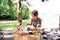 Little girl camping in forest eating grilled food.