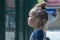 A little girl carefully looks over the fence at the children`s playground. Concept: the desire to play sports, the limitations of