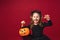 Little girl in cat costume with mustache and ears, with pumpkin in her hands