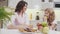 Little girl and charming woman sitting at table in kitchen